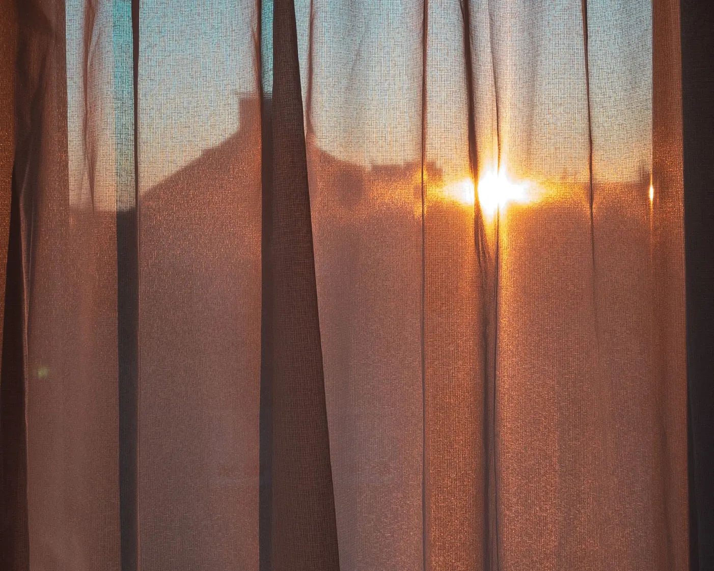 Morning sun rising through a linen curtain